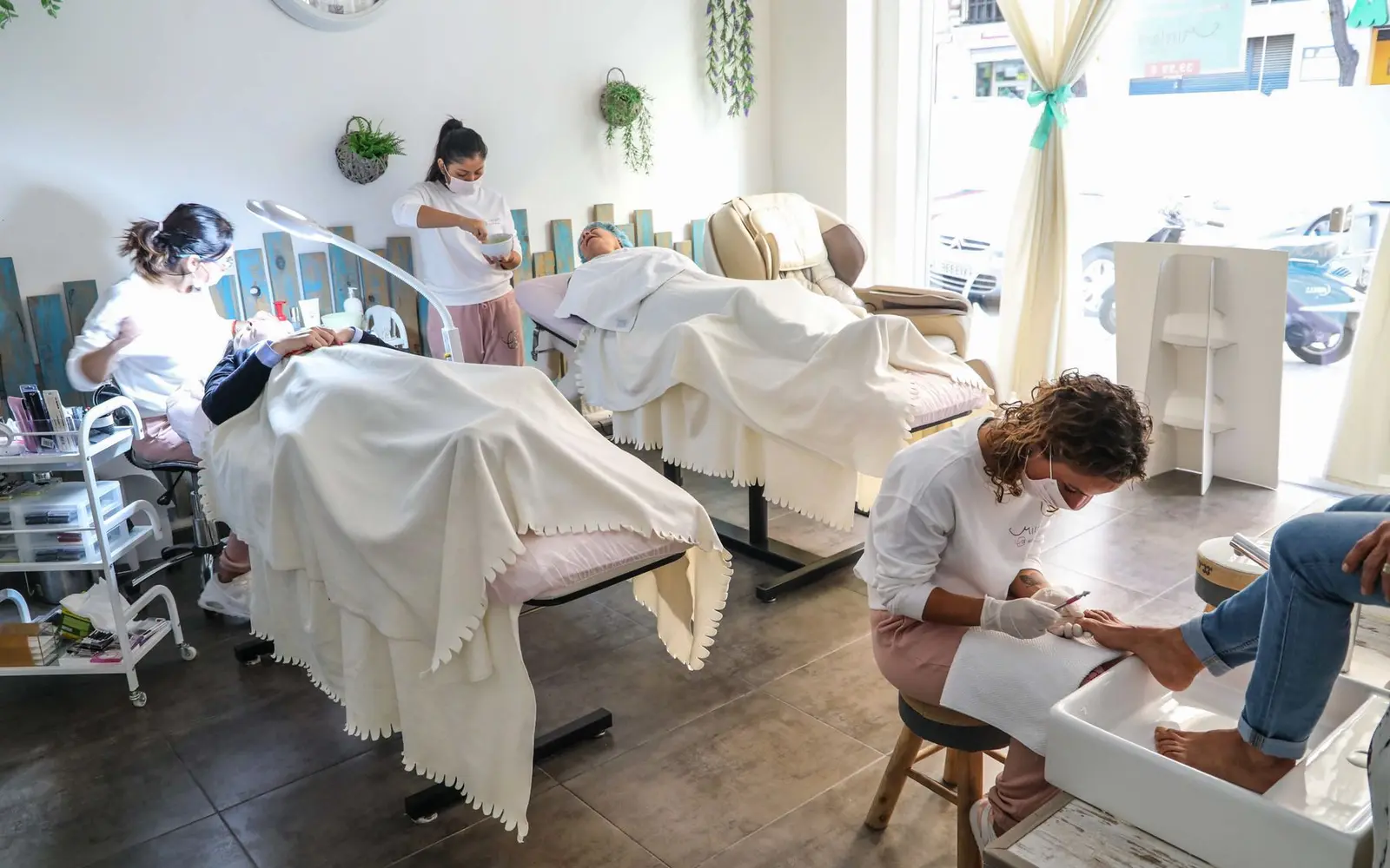 Ferah bir güzellik salonunda yüz bakımı ve pedikür uygulayan uzmanlar