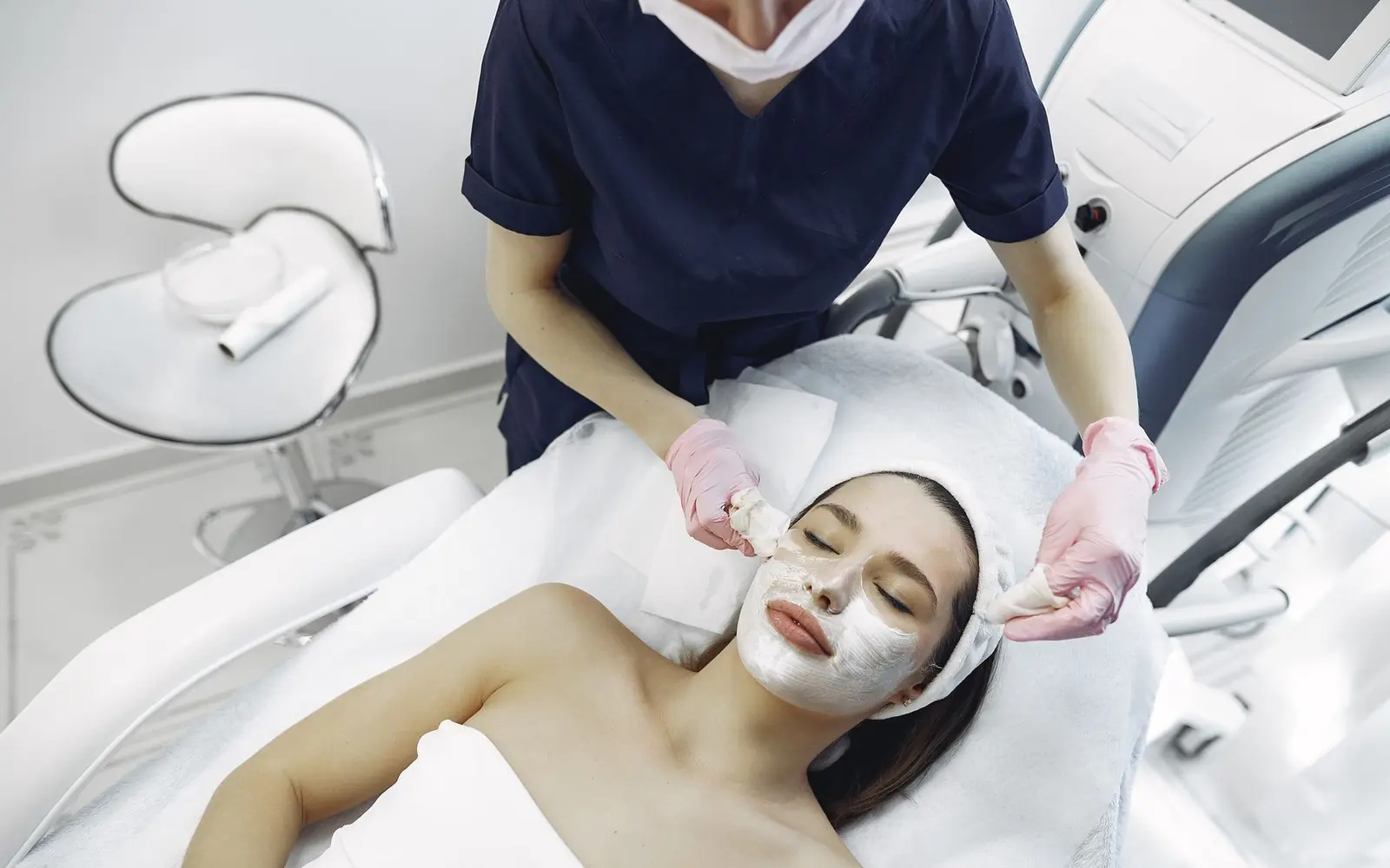 Dermatoloji uzmanı eldivenle danışanın yüzünü temizliyor
